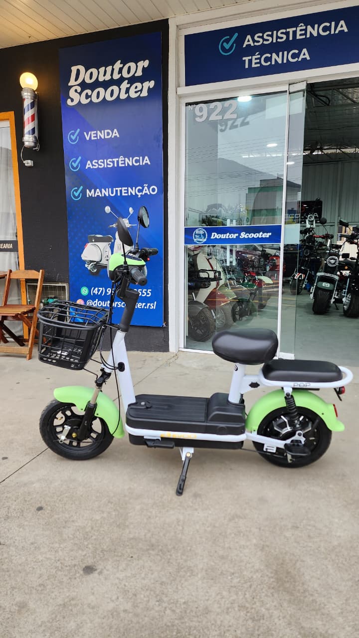 Scooter elétrica verde e branca em frente à loja